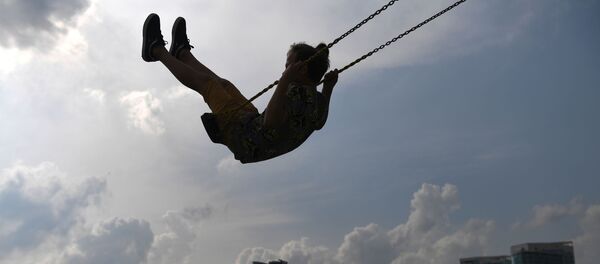 Девочка катается на качелях в парке, архивное фото - Sputnik Литва