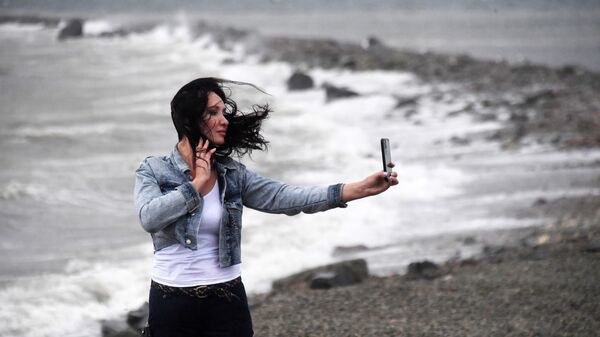 Девушка фотографируется на побережье во время сильного ветра, архивное фото - Sputnik Литва