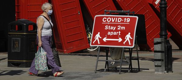 Женщина в медицинской маске и плакат с призывом соблюдать социальную дистанцию на фоне скульптуры британского скульптора Дэвида Маха Out of Order в Лондоне, Великобритания  - Sputnik Литва