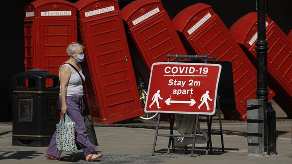 Женщина в медицинской маске и плакат с призывом соблюдать социальную дистанцию на фоне скульптуры британского скульптора Дэвида Маха Out of Order в Лондоне, Великобритания  - Sputnik Lietuva