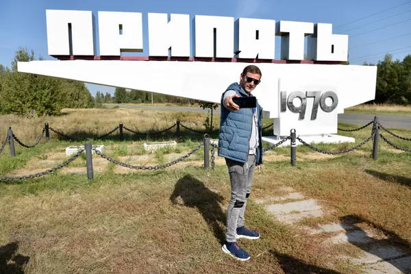 Турист фотографируется у стеллы Припять