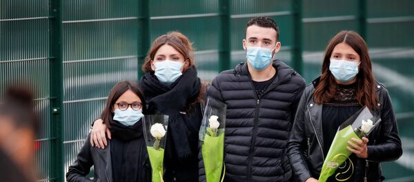 Люди несут цветы к месту гибели преподавателя в коммуне Конфлан-Сент-Онорин недалеко от Парижа Люди несут цветы к месту гибели преподавателя в коммуне Конфлан-Сент-Онорин недалеко от Парижа - Sputnik Lietuva