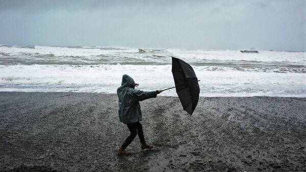 Женщина с зонтом на берегу моря во время сильного ветра, архивное фото - Sputnik Литва