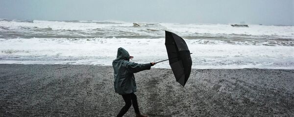 Женщина с зонтом на берегу моря во время сильного ветра, архивное фото - Sputnik Литва