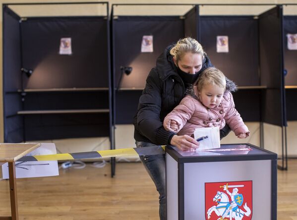 Женщина с ребенком опускает свой бюллетень на избирательном участке во время второго тура парламентских выборов в Вильнюсе, 25 октября 2020 года - Sputnik Lietuva