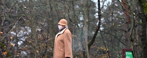 Женщина в защитной маске на улице в Вильнюсе Женщина в защитной маске на улице в Вильнюсе - Sputnik Литва
