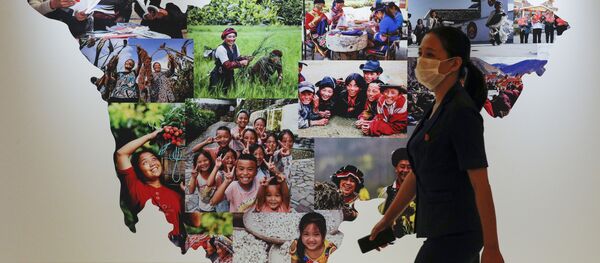 Женщина в защитной маске проходит мимо карты провинции Сычуань Женщина в защитной маске проходит мимо карты провинции Сычуань - Sputnik Lietuva