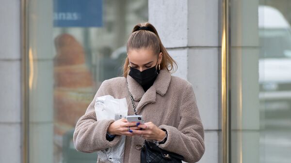 Девушка в защитной маске и мобильным на улице в Вильнюсе - Sputnik Lietuva