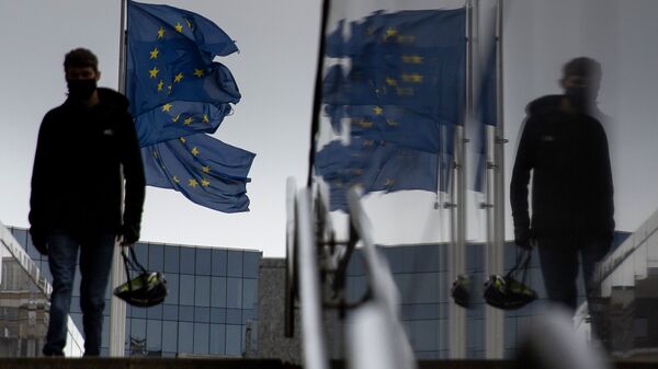 Мужчина идет мимо флагов ЕС у штаб-квартиры ЕС в Брюсселе - Sputnik Литва