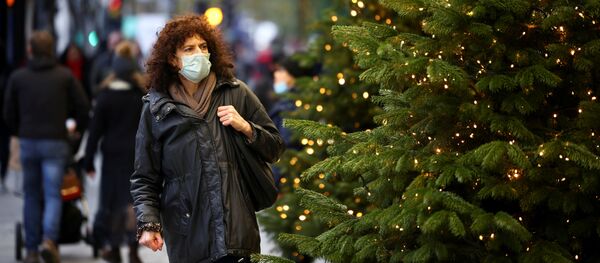 Женщина проходит мимо рождественских елок на Оксфорд-стрит, Лондон, Великобритания - Sputnik Литва