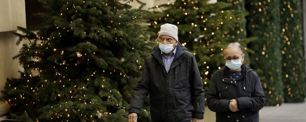 Люди в масках проходят мимо рождественских елок в Лондоне Люди в масках проходят мимо рождественских елок в Лондоне - Sputnik Литва
