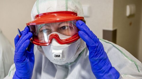 Медработник в защитном костюме в Вильнюсской университетской клинической больнице Сантарос  - Sputnik Литва