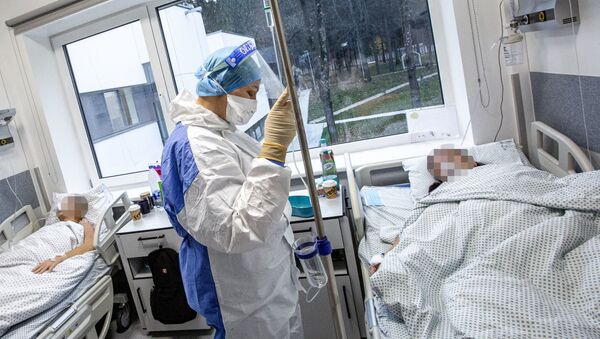 Медработник в защитном костюме в Вильнюсской университетской клинической больнице Сантарос - Sputnik Литва