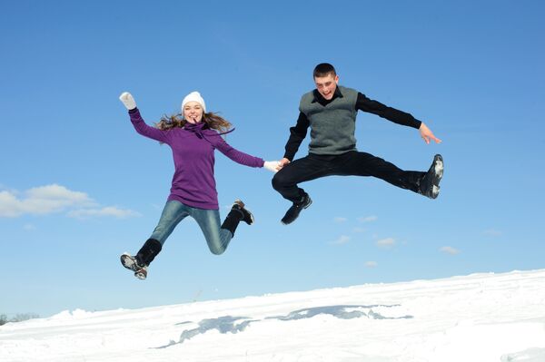 Подпрыгнувшая пара на фоне снега и голубого неба - Sputnik Литва