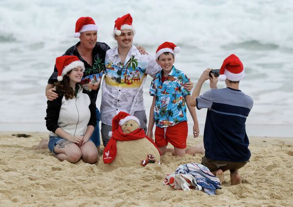 Семья в рождественских колпаках фотографируется на пляже в Сиднее, Австралия  - Sputnik Литва