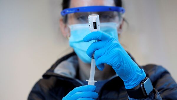 Медицинский работник набирает в шприц вакцину против коронавируса - Sputnik Литва
