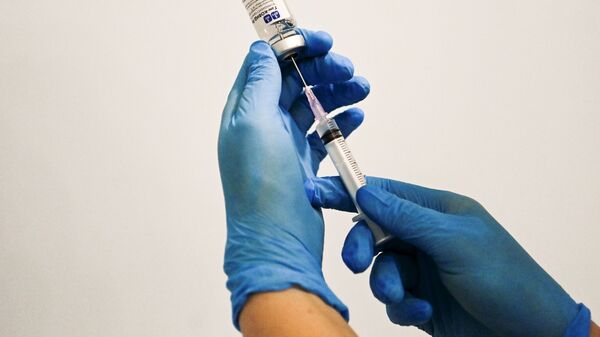 Медицинский сотрудник держит в руках вакцину Спутник V в пункте вакцинации - Sputnik Литва