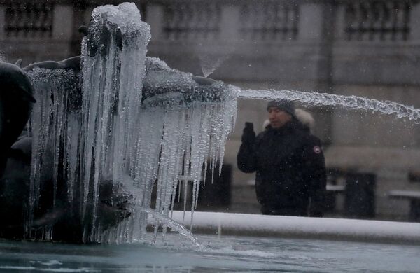 Мужчина фотографирует покрытую льдом статую на Трафальгарской площади в Лондоне - Sputnik Литва