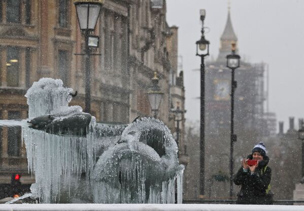 Женщина фотографирует покрытую льдом статую на Трафальгарской площади в Лондоне - Sputnik Lietuva