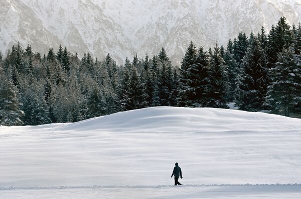Мужчина идет сквозь снег недалеко от Гармиш-Партенкирхена, Германия - Sputnik Lietuva