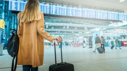Девушка с чемоданом, паспортом и билетом в зале ожидания