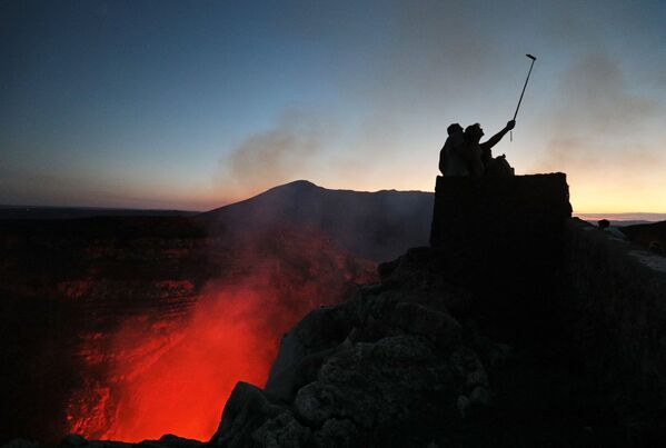 Туристы фотографируются у кратера вулкана Масая в Национальном парке Никарагуа. Индейцы называют вулкан Попогатепе, что в переводе означает огненная гора. Испанские завоеватели называли вулкан La Boca del Infierno (Адская глотка). Последнее извержение произошло в 2008 году. - Sputnik Литва