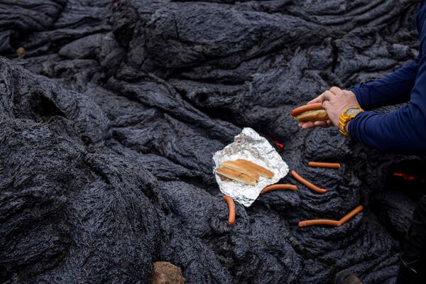 Мужчина готовит хот-доги на вулканическом участке на полуострове Рейкьянес после извержения вулкана. - Sputnik Литва