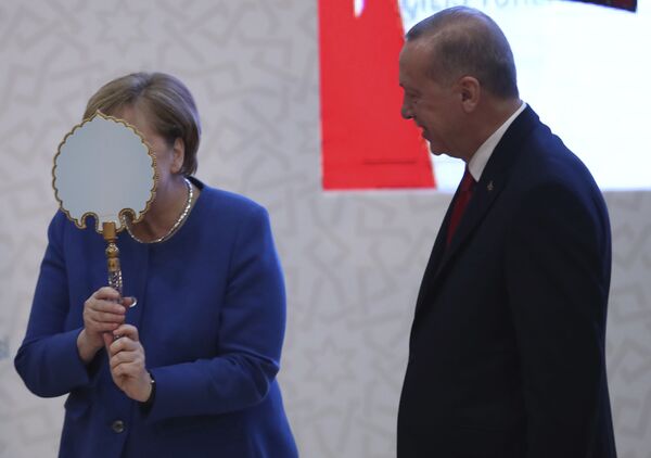 Vokietijos kanclerė Angela Merkel prisidengia veidrodžiu, kurį jai dovanojo Turkijos prezidentas Tajipas Erdoganas, per vizitą Stambule 2020 metų sausio mėnesį. Tokie veidrodžiai su brangiais rėmais ir rankenomis buvo naudojami rūmuose ir simbolizuoja galią, prabangą ir turtus. - Sputnik Lietuva