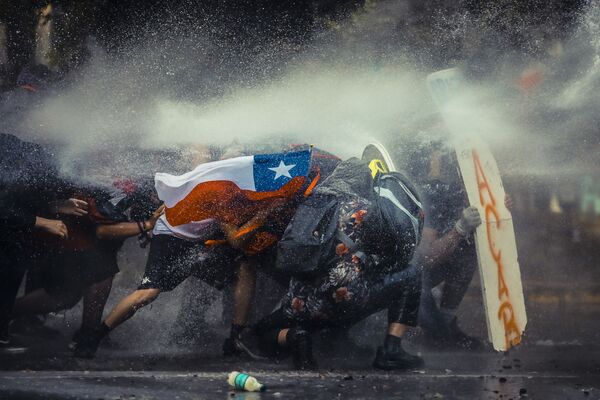 Čilės fotografo Javier'o Vergar'os nuotrauka Chile Resists autoriui uždirbo penktąją vietą ir 500 USD. Nuotraukoje demonstrantai skydu prisidengia nuo vandens patrankos, kurią specialiosios pajėgos naudojo per protestus 2019 metų lapkričio 11 dieną. - Sputnik Lietuva