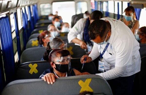 Meksikoje visi gamyklų darbuotojai yra paskiepyti. Gydytojai skiepija tiesiog autobuse, vežančiame darbininkus į gamyklą Siudad Chuarese. - Sputnik Lietuva
