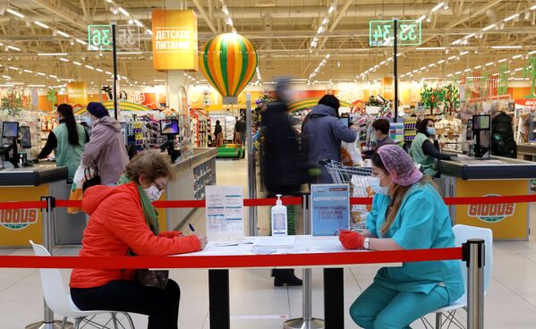 Rusijoje galite pasiskiepyti tiesiai prekybos centre. Nuotraukoje: moteris priešais Maskvos prekybos centrą &quot;Globus&quot;, pasiskiepijusi vakcina &quot;Sputnik V&quot;, pildo dokumentus. - Sputnik Lietuva