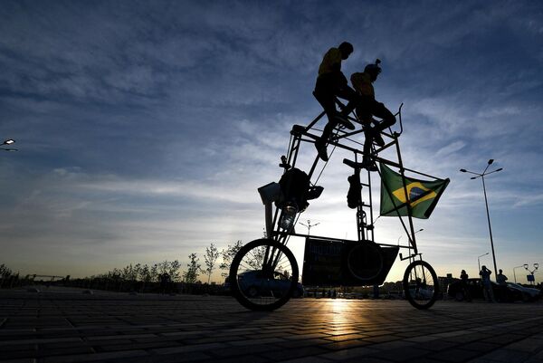 Nuotraukoje: Brazilijos futbolo sirgaliai Eliasas de Souza ir jo sūnus Eliasas de Souza jaunesnysis važinėja 3 metrų aukščio dviračiu šalia Rostovo arenos, Rusija. - Sputnik Lietuva