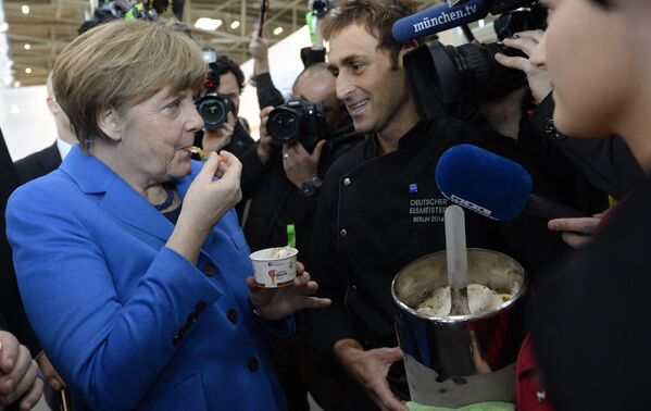 Vokietijos kanclerė Angela Merkel ragauja ledus, kuriuos jai davė Vokietijos &quot;Gelato&quot; čempionas 2014 Adriano Colle (C), kai ji 2015 metų kovo 13 dieną lankėsi &quot;Internationale Handwerksmesse&quot; mugėje Miunchene. - Sputnik Lietuva