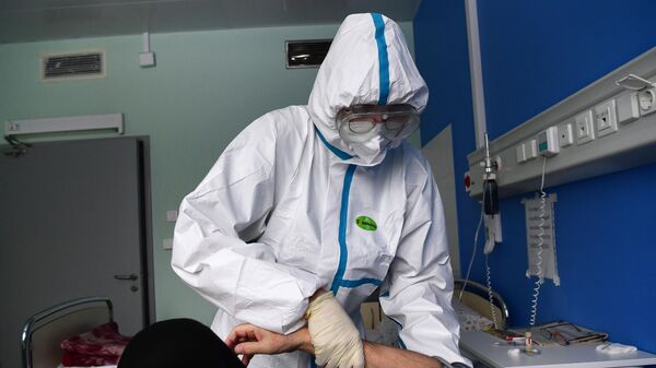 Врач работает с пациентом в палате госпиталя для больных коронавирусом - Sputnik Литва