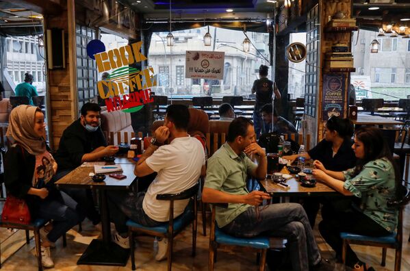 Klientai sėdi kavinėje, kurioje siūloma nemokama kava žmonėms, kurie pasiskiepijo COVID-19 vakcina Bagdade, Irake, 2021 metų gegužės 22 diena. - Sputnik Lietuva