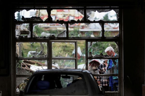 Žmonės žiūri pro sugadintą langą po viesulo, kuris sunaikino kai kurias gyvenvietes. - Sputnik Lietuva