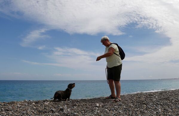 2021 metų birželio 23 dieną Nicoje, Prancūzijoje, Promenade des Anglais, atidarius šunų paplūdimį moteris vaikšto su savo šunimi. - Sputnik Lietuva