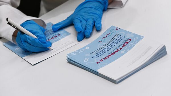 Медицинский сотрудник подписывает сертификат в центре вакцинации от COVID-19 в Москве - Sputnik Литва