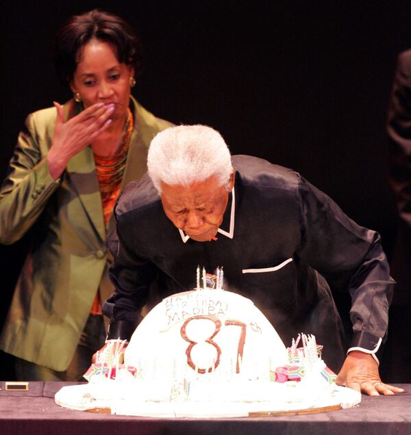 Buvęs Pietų Afrikos prezidentas Nelsonas Mandela per 87-ąjį gimtadienį užpučia žvakes per trečiąją Nelsono Mandelos metinę paskaitą, 2005 metų liepos 19 d,. Johanesburgas. - Sputnik Lietuva