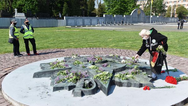 Женщина возлагает цветы на военном кладбище Марсово поле во Львове - Sputnik Литва