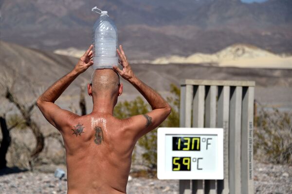Stivas Krofchikas iš Las Vegaso bando atsigaivinti su ledo buteliu ant galvos, kai termometras rodo 54,4 laipsnius pagal Celsijaus skalę, o ekrane yra mechaninis gedimas, dėl kurio skaičiai pateikiami neteisingai, „Furnace Creek“ lankytojų centre Mirties slėnyje, Kalifornija, JAV - Sputnik Lietuva