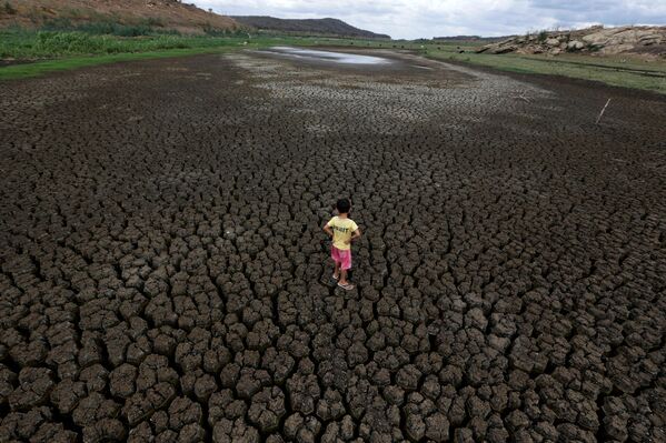5 metų berniukas stovi ant sutrūkinėjusios Boqueirao rezervuaro žemės Campina Grande metropolijos regione, Paraibos valstijoje, Brazilijoje. - Sputnik Lietuva