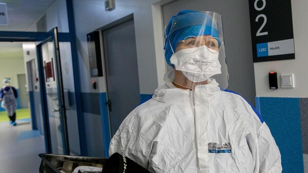 Медработник в защитном костюме в Вильнюсской университетской клинической больнице Сантарос - Sputnik Литва