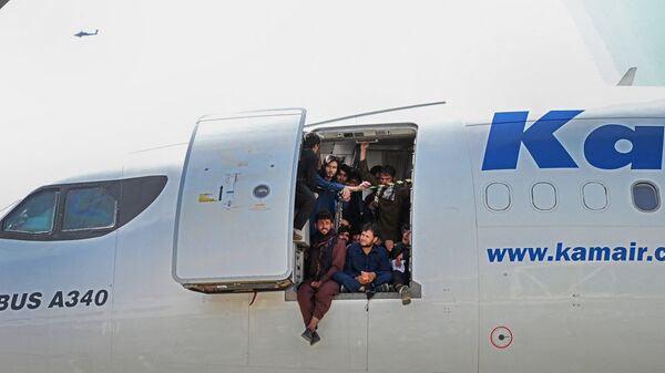 Афганцы сидят в дверях самолета в аэропорту Кабула - Sputnik Литва