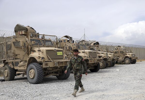 Afganistano armijos kareivis eina pro minoms atsparias  transporto priemones MRAP, kurios buvo paliktos po to, kai amerikiečiai išvyko iš Bagramo oro pajėgų bazės. - Sputnik Lietuva
