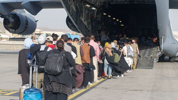 Афганские беженцы во время посадки на самолет C-17 Globemaster III ВВС США в международном аэропорту имени Хамида Карзая в Кабуле - Sputnik Литва
