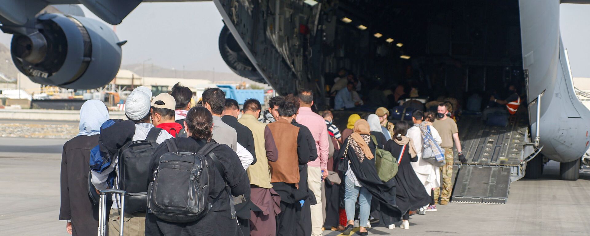 Афганские беженцы во время посадки на самолет C-17 Globemaster III ВВС США в международном аэропорту имени Хамида Карзая в Кабуле - Sputnik Литва, 1920, 24.08.2021