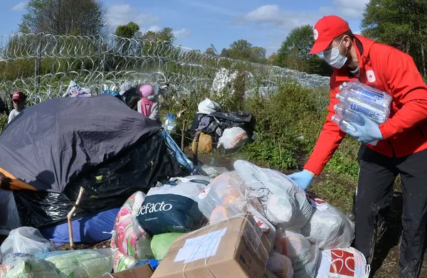 Baltarusijos Raudonojo Kryžiaus aktyvistai palieka humanitarinę pagalbą pabėgėlių iš Afganistano stovykloje, Baltarusijos ir Lenkijos pasienyje. - Sputnik Lietuva