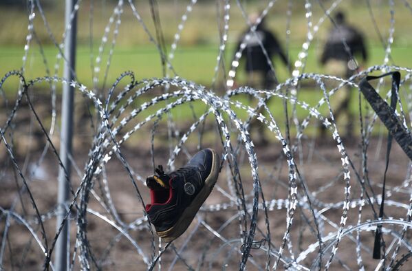 Pabėgėliai iš Afganistano džiauna drabužius ir batus ant spygliuotos tvoros. - Sputnik Lietuva