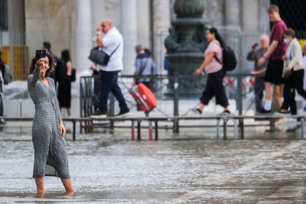 Moteris fotografuojasi užtvindytoje Šv. Morkaus aikštėje, pakilus vandens lygiui Venecijoje, Italijoje, 2021 metų spalio 5 dieną. - Sputnik Lietuva